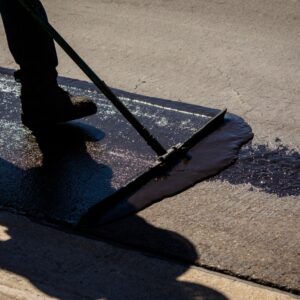 Worker,Using,A,Sealcoating,Brush,During,Asphalt,Resurfacing,Project