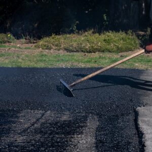 Construction,Worker,With,Asphalt,Rake,Smoothing,Out,Fresh,Blacktop,On